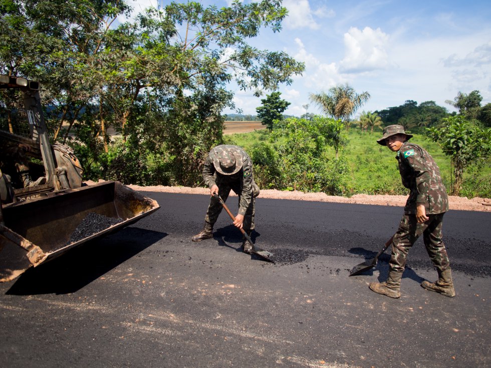 Soldiers pave some of the last miles of BR-163, a highway cutting through the Amazon basin which Bolsonaro had pledged to complete. For years, trucks carrying grain for export have lumbered along this slow, muddy road. Its completion significantly reduces transport time. Image by Heriberto Araújo. Brazil, 2019. Soldiers pave some of the last miles of BR-163, a highway cutting through the Amazon basin which Bolsonaro had pledged to complete. For years, trucks carrying grain for export have lumbered along this slow, muddy road. Its completion significantly reduces transport time. Image by Heriberto Araújo. Brazil, 2019.