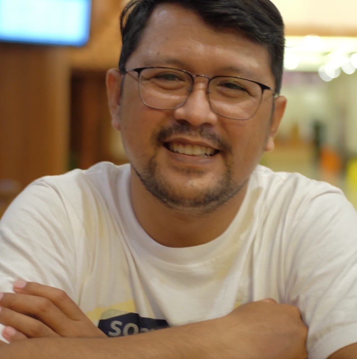 A man with glasses smiles into the camera.