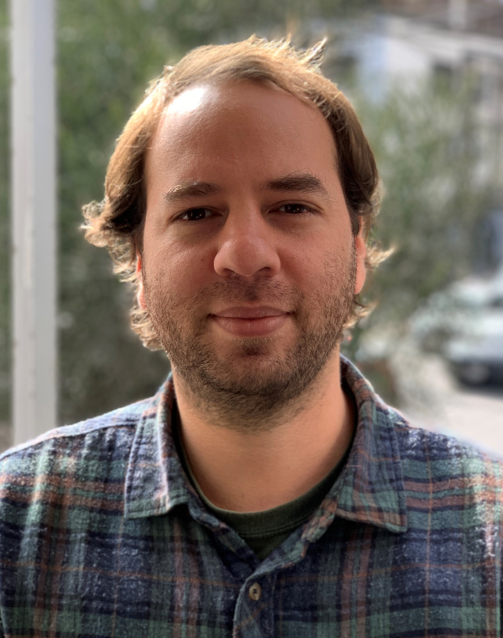 A man with facial hair and wears a striped shirt.