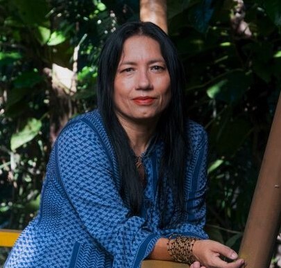 A woman wears a blue-striped shirt with a bracelet. She has black hair and looks at the camera.
