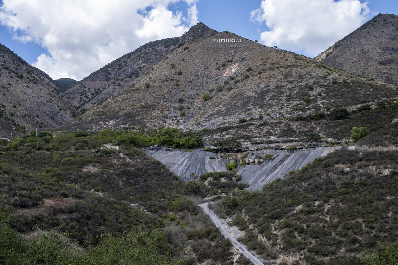 The Mercury Route A mine at the base of a mountainscape. 'Carmago' is emblazoned on the center peak.