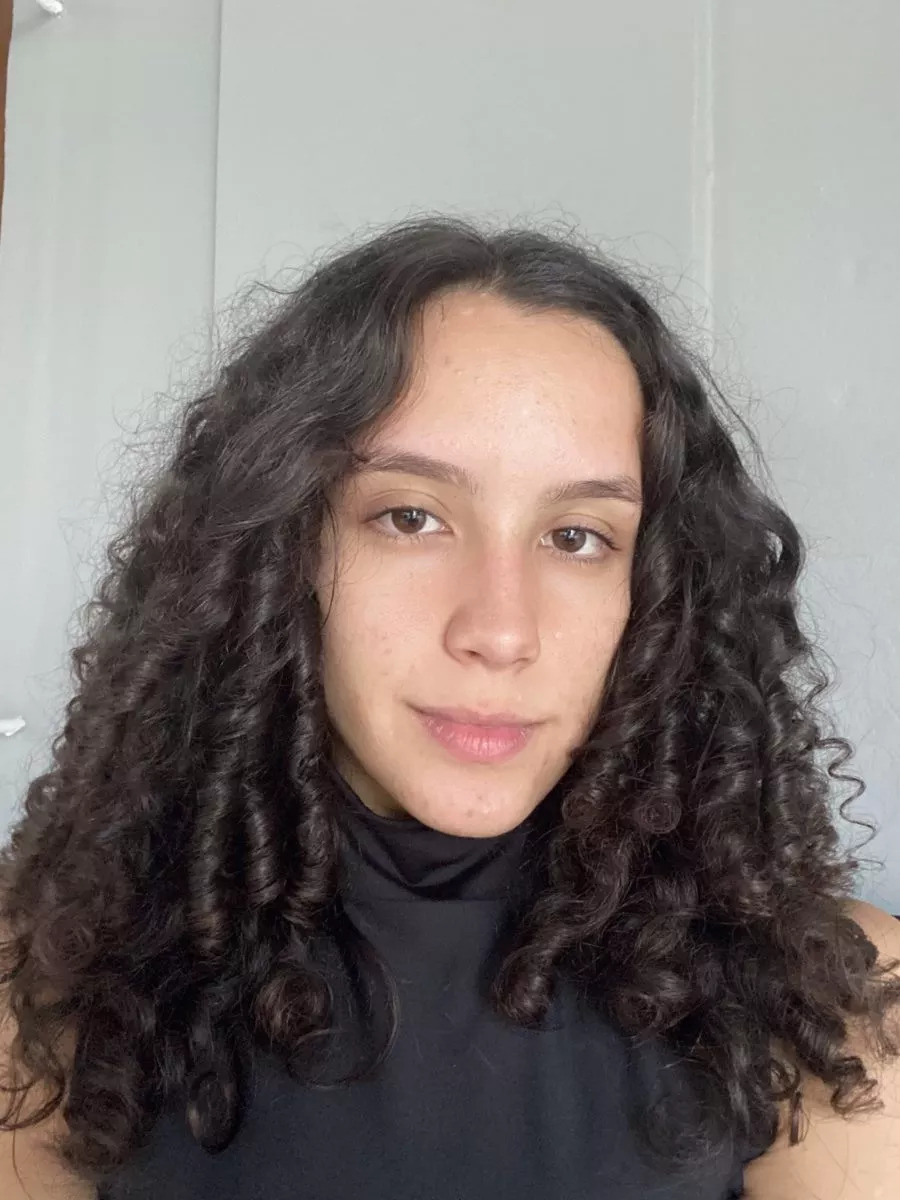 a woman with curly hair looks into the camera