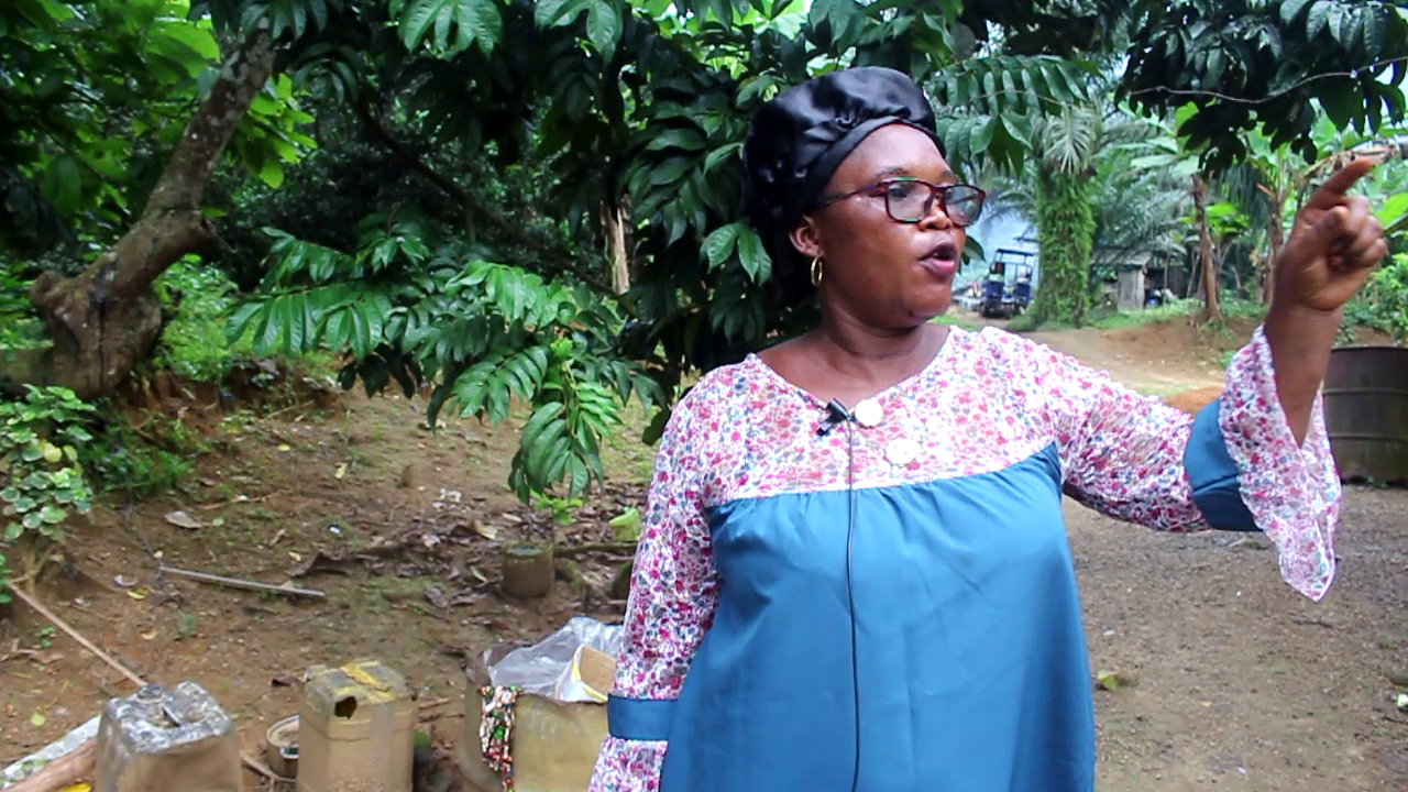 A woman in blue and pink shirt points to her right.