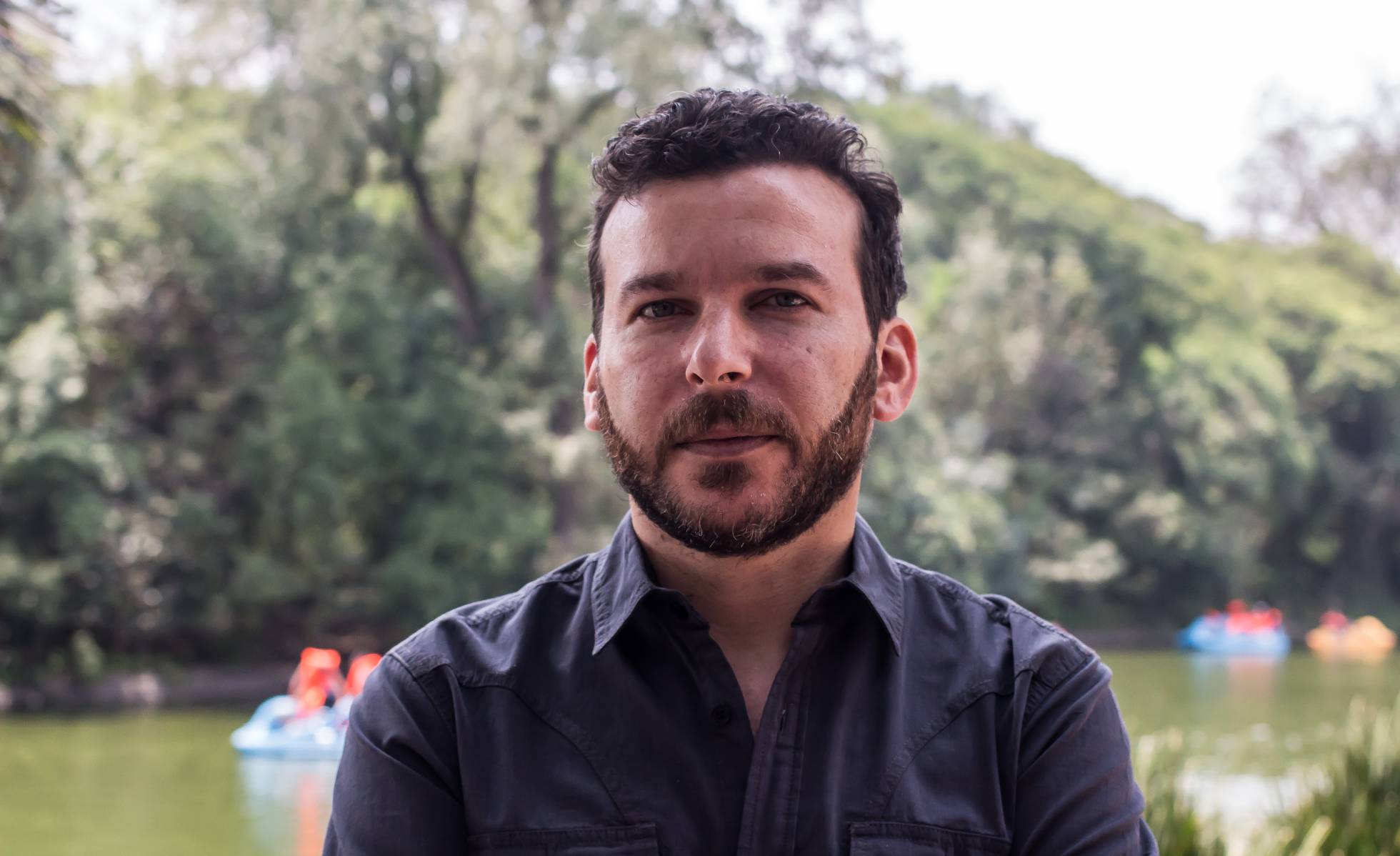Headshot of a man with short dark hair wearing a navy button down