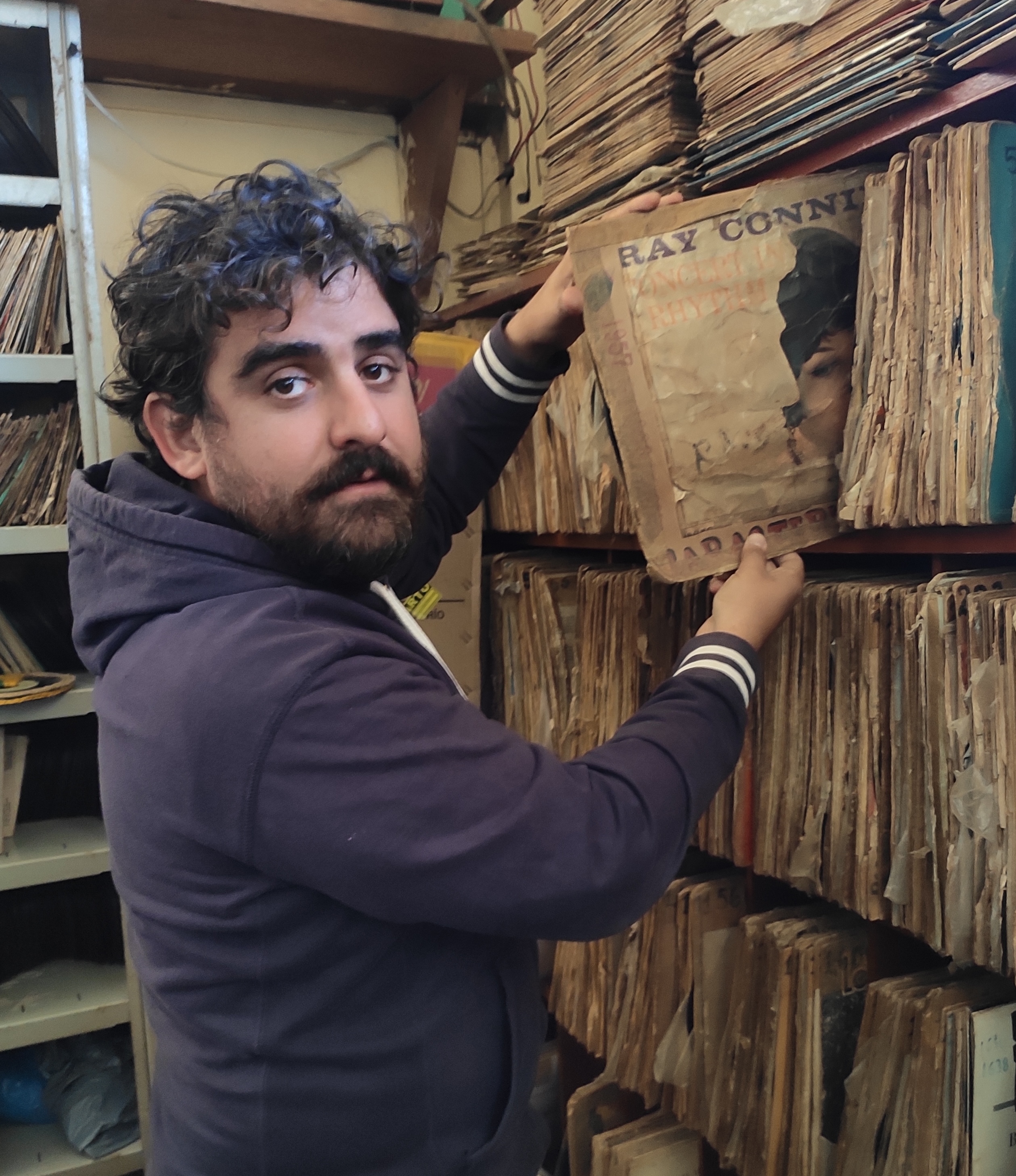 Cesar is putting an old book back into the shelf.