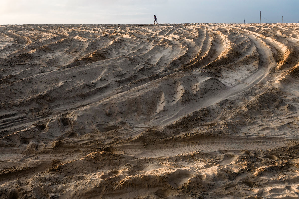 A boy walks atop massive sand dunes.