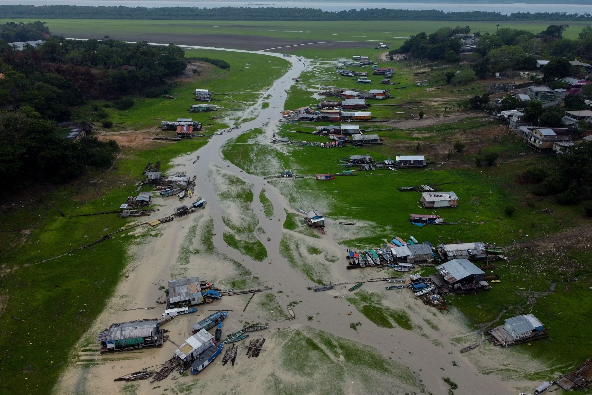 Floating houses and boats lie stranded on a soaked up river during an abnormal dry season.