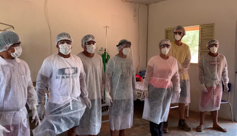 Doctors and nurses are standing up inside a health clinic. They are wearing personal protective equipment (PPE). 