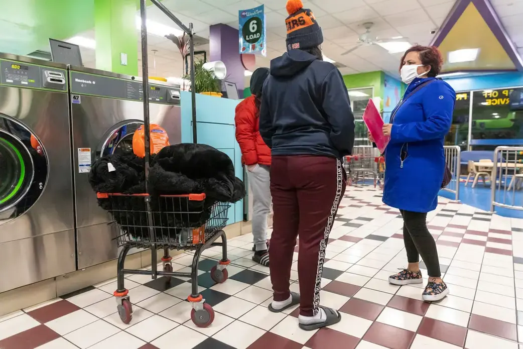 Margarita Sanchez, a promotora de salud — community health worker — with Centro San Bonifacia, conducts a survey about COVID-19 and helps answer questions for people on Jan. 15, 2021, at a laundromat in Belmont Cragin on Chicago's Northwest Side. Manuel Martinez / WBEZ News.
