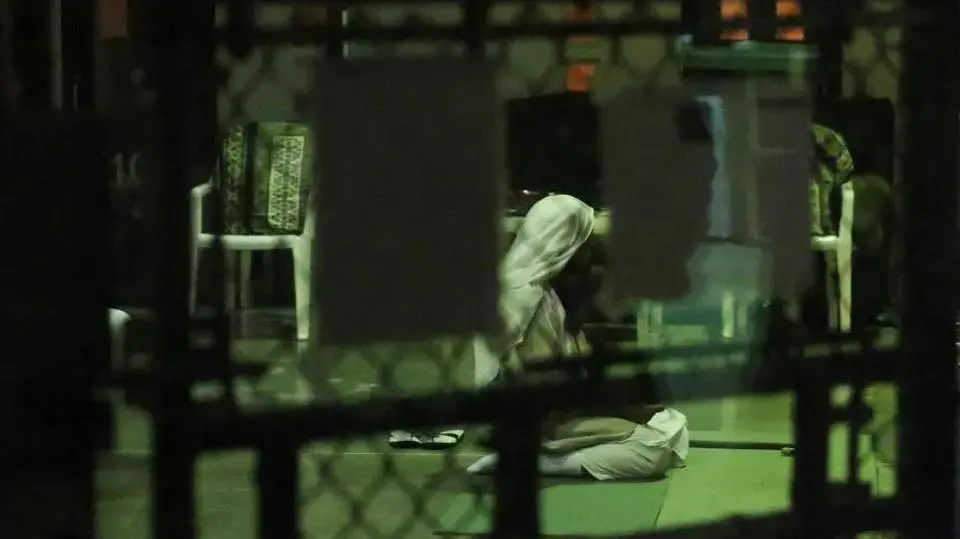 A detainee kneels in prayer at sunset on February 11, 2017, at Camp Six at Guantánamo’s Detention Center Zone. The military approved release of this photo. Image courtesy of Emily Michot/McClatchy. Cuba, 2019.