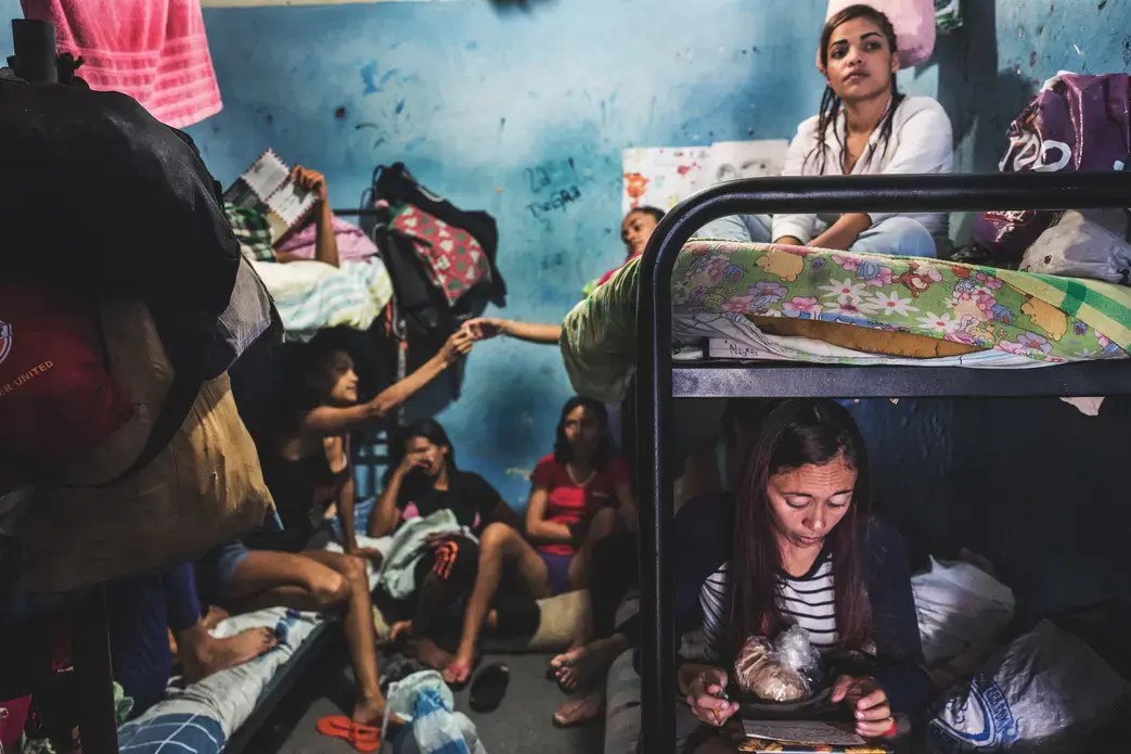 LA YAGUARA CENTER OF DETENTION, CARACAS - March 2018. Women inside a preventive detention center spend their days in a deranged inactivity. They adapte their space of their “dungeon” to make it look more like a home. They write letters or make drawings to their children, read the Bible, share cigarettes or iron their hair. Image by Ana María Arévalo. Venezuela, 2018.