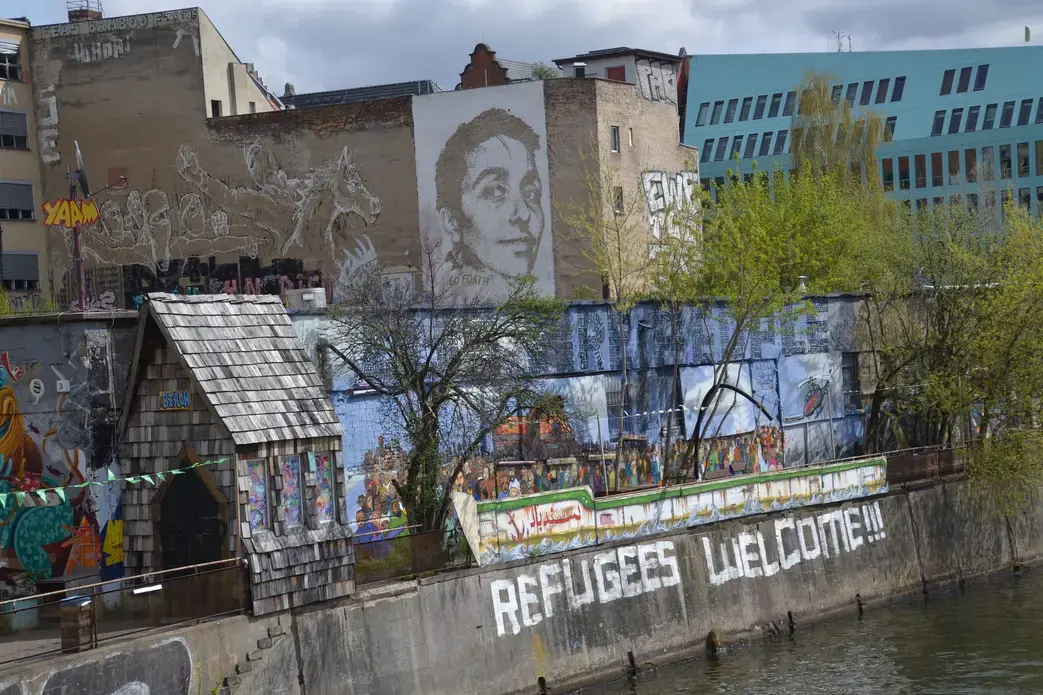 A mural in Berlin says "Refugees Welcome." Image by Jeanne Menjoulet. Berlin, 2016.