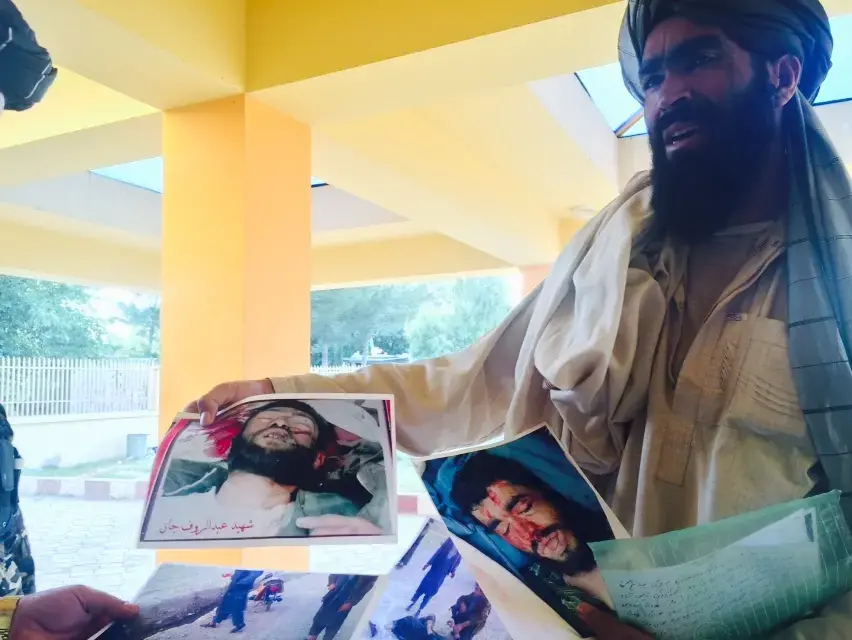 A man holds photographs of his and others' family members, victims of Abdul Hakim Shujayi, a US-funded militia commander in Uruzgan, Afghanistan.