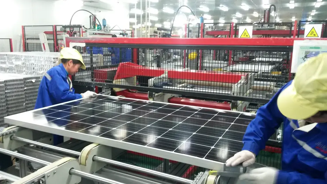 Workers assemble a solar panel inside of a factory in Haining, Zhejiang province, China.
