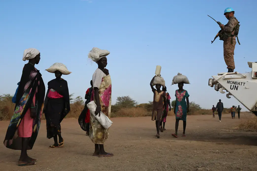 Internally displaced South Sudanese walk past a U.N. peacekeeper in Bentiu. Image by Cassandra Vinograd. South Sudan, 2016.