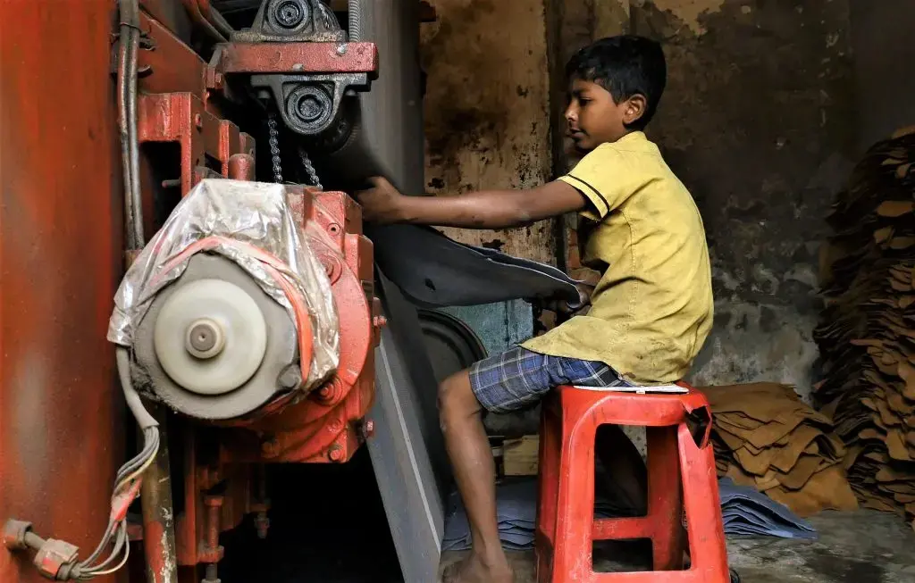 A 10-year-old boy pulls a hide from pressing machine at a tannery in Dhaka, the capital of Bangladesh. Image by Justin Kenny. Bangladesh, 2016.
