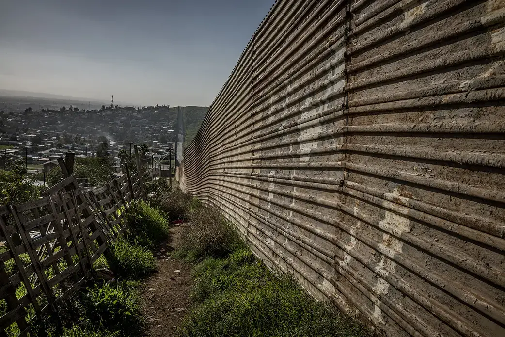 A pattern quickly establishes itself along most of the border fence that separates Baja California, Mexico from California, USA - Mexican urban centers press up against the U.S. border, as if to draw heat from its economic heat, while California cities seem to push back and away from the border, as seen here in Nido de las Águilas (Eagle's Nest) in the east of an expanding Tijuana metropolis. Image by James Whitlow Delano. Mexico, 2017.