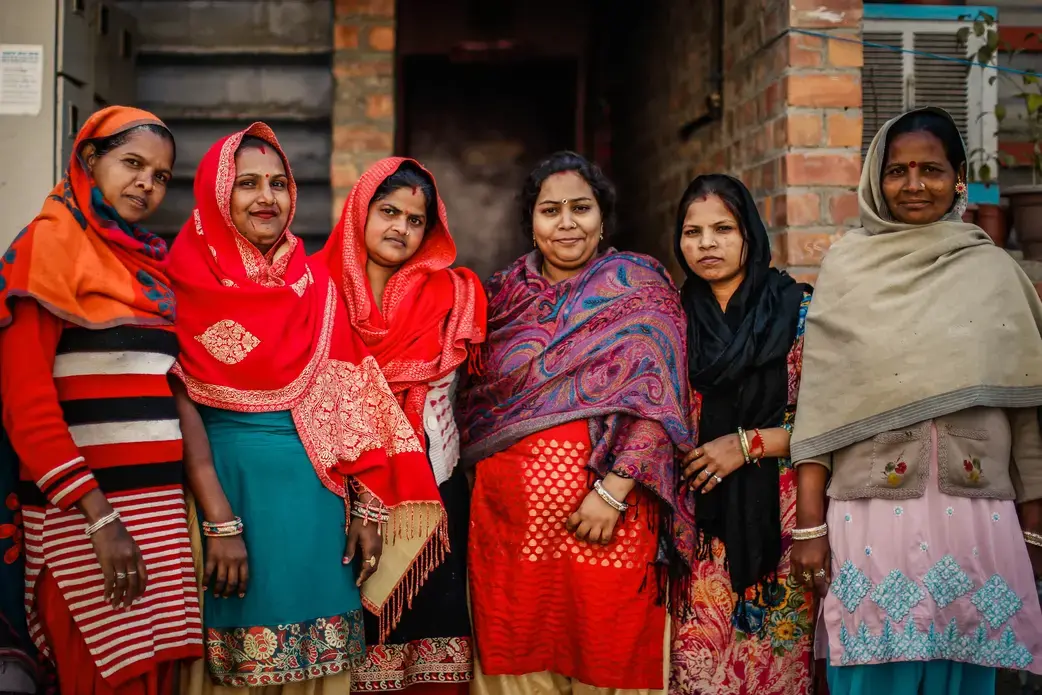 A group of female housing rights activists stand in front of their relocation flats in Baprola, New Delhi. Image by Kiran Misra. India, 2019.