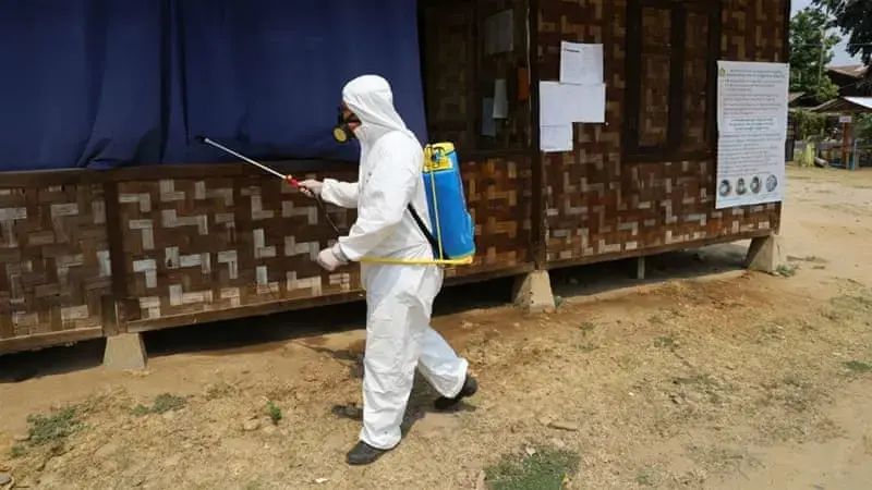 A volunteer from the Kachin State COVID-19 Prevention network sprays disinfectant at a camp in Myitkyina, Kachin state. Image courtesy Al Jazeera. Myanmar, 2020.