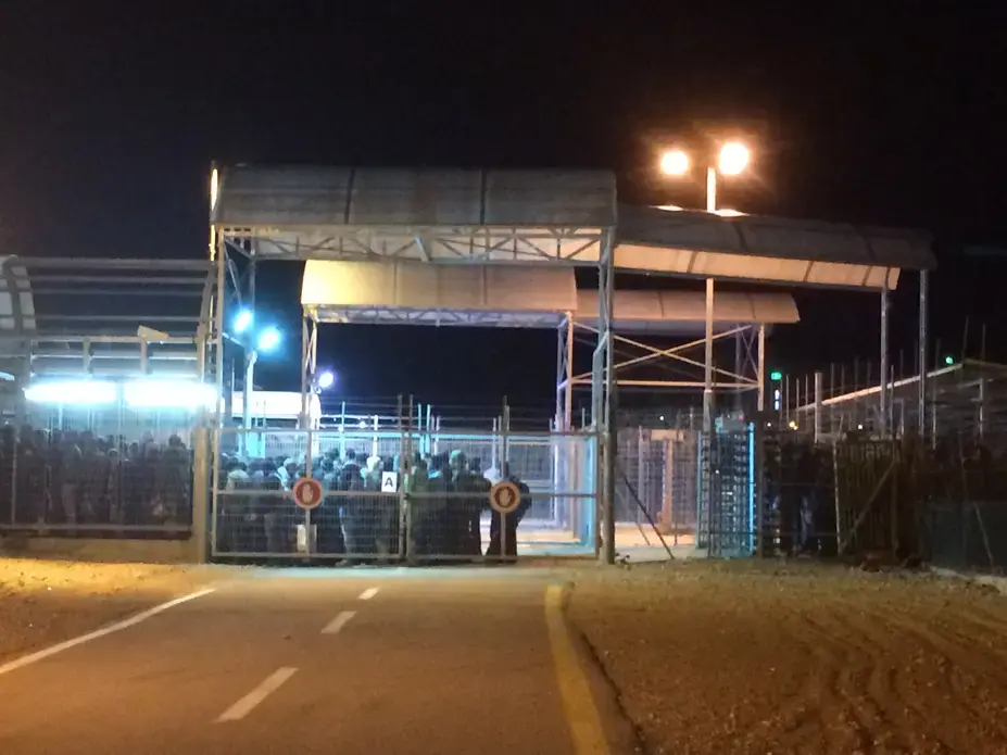 Palestinian men who labor in Israel wait to cross from the Palestinian to the Israeli side of the Eyal checkpoint before sunrise in February. Image by Miriam Berger. Israel, 2017. 