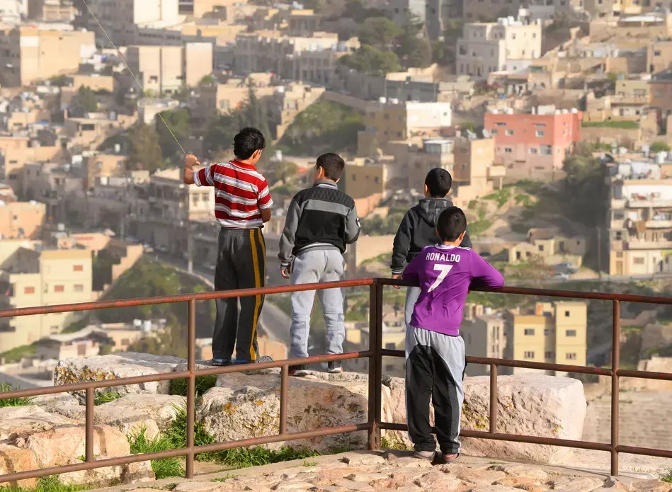 Group of local Jordanian children and city skyline out of focus from the Citadel Hill, Jabal. Image by Thiago B Trevisan / Shutterstock.com. Jordan, 2018.