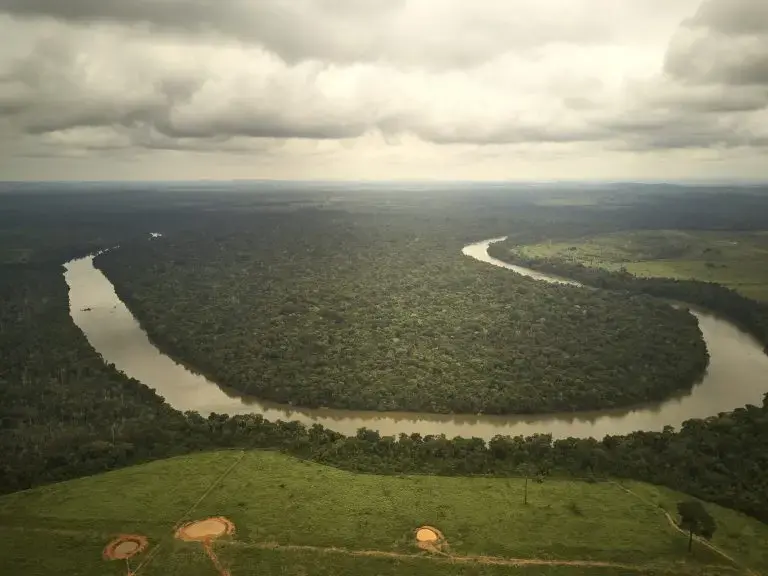 Visão aérea de um trecho no rio dos Peixes onde se pode ver o contraste entre a área desmatada na margem não indígena do rio e a área preservada dentro da Terra Indígena na outra margem. Image by: Pablo Albarenga. Brazil, 2019.