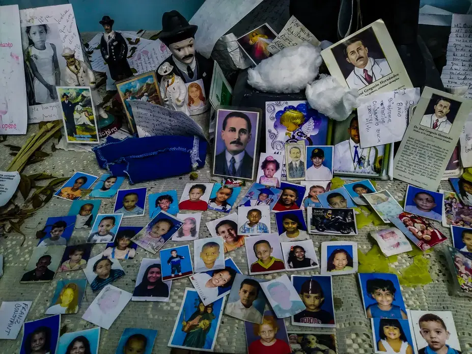 An improvised altar in honor of José Gregorio Hernández at the Hospital J.M de los Ríos. Hernández, a Venezuelan doctor widely known and remembered by his kindness and service to the poor, is considered a saint by many Catholics in Venezuela, who often think of him as the protector of the ill. At the pediatric hospital, mothers and family members put photos of their children at the altar to pray for their good health and swift recovery. Image by Flaviana Sandoval. Venezuela, 2018.