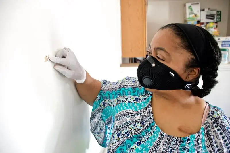 Kim Daniel shows where a bullet fired from a nearby apartment entered her unit. Image by Wiley Price/St. Louis American. United States, 2020.