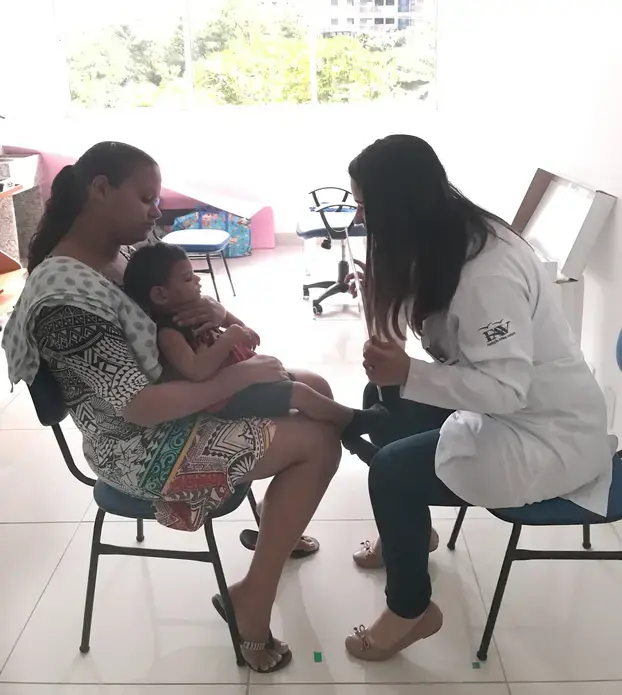 Dr. Isabella Santana, an ophthalmologist at the Altino Ventura Foundation in Recife, Pernambuco, conducts a visual exam with Pedro, a young child born with microcephaly associated with Zika virus, while his mother Juliana holds him. To date, the Altino Ventura Foundation has diagnosed 322 babies with congenital Zika syndrome. Image by Poonam Daryani. Brazil, 2017.