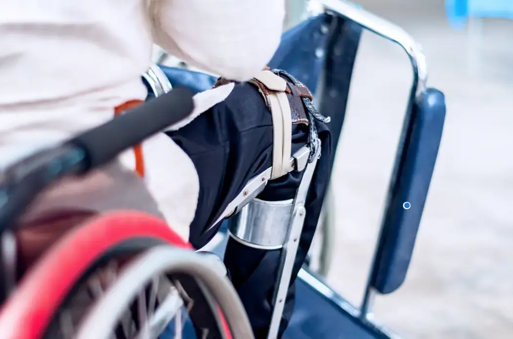 A man sitting on the wheelchair with an old polio knee brace, closeup view. Image by Ruchuda Boonplien / Shutterstock. Undated.