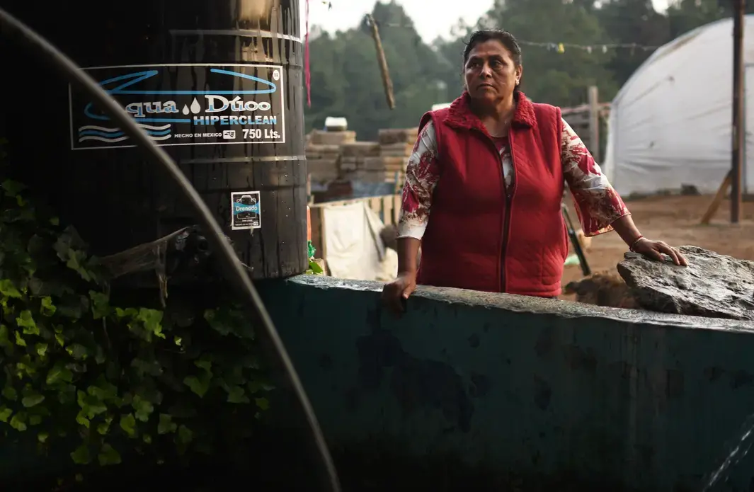 Margarita Reyes takes a break after finishing her typical water gathering routine, which requires her to haul a large pump down to a nearby river. Reyes has lived on the same property her entire life and has watched the Cutzamala System invade her community. She has never had running water in her home despite the proximity of the system. Image by Meg Vatterott. Mexico, 2018.