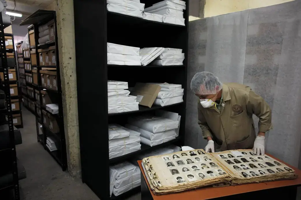 Wearing a mask and gloves to protect fragile documents, an archivist opens one of the thousands of books of photographs held by the Historical Archives of the National Police. The Guatemalans pictured inside were all detained or arrested by the National Police during the country’s long civil war. Many of their fates remain unknown. Sometimes, visitors to the archive—or the archivists themselves—will turn a page and recognize a friend or relative not seen in decades. Image by Lynn Johnson. Guatemala, 2017.