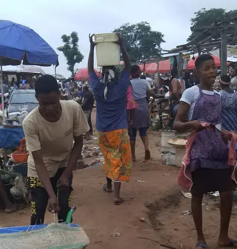 A woman carries a bucket of water on her head at Gosa market. Image by Anita Igbine. Nigeria, 2020.