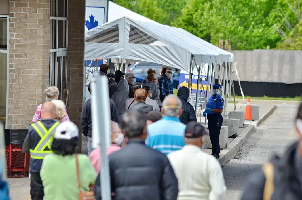 People wait in line for a COVID-19 test at a pop-up mobile Assessment Centre. Image by Bob Hilscher/Shutterstock. Canada, 2020.