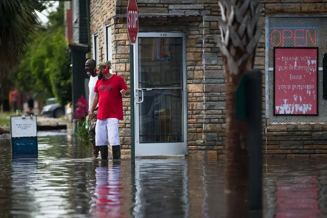People walk out of President Market during flooding on Wednesday, May 20, 2020, in Charleston. The market is just across from the Gadsden Green public housing complex. Image by Andrew Whitaker / The Post and Courier. United States, 2020.
