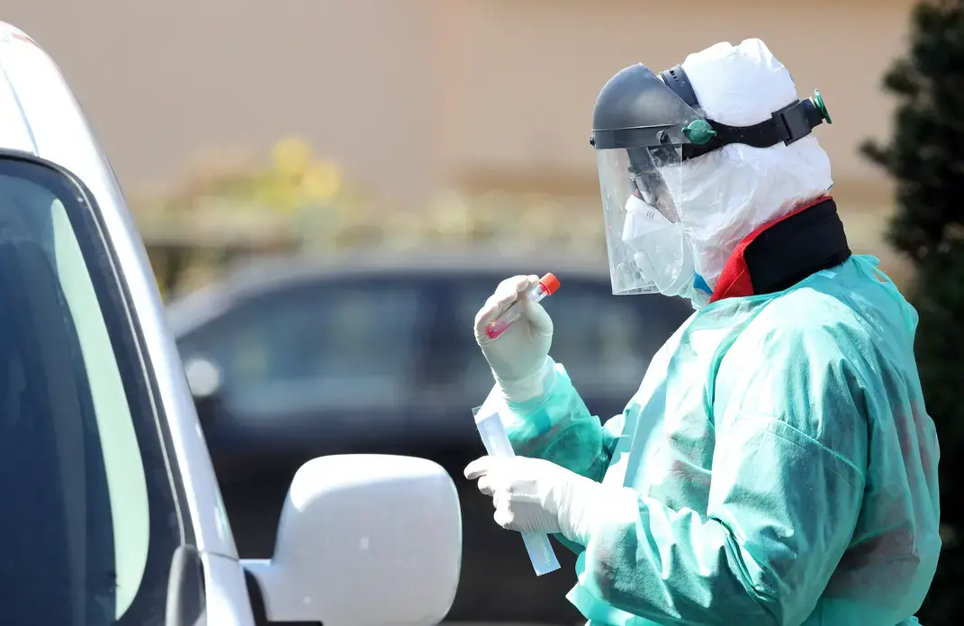 Medical staff member performs coronavirus tests at drive-thru testing point. Image by Damir Sencar / Shutterstock. Croatia, 2020.