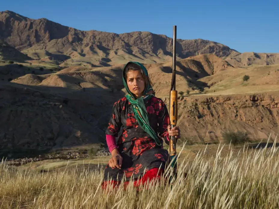 In Khuzestan Province, Masoumeh Ahmadi, 14, holds her mother’s shotgun. After a woman marries, she receives a firearm—with the approval of her husband and her father. Many women get one as a gift from their husbands after giving birth to their first son. Image by Newsha Tavakolian. Iran, 2018.