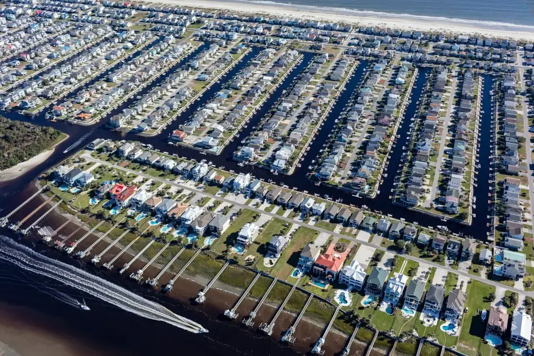 Ocean Isle Beach, a densely packed resort community in North Carolina, sits mostly on a tiny barrier island about as long as six Brooklyn Bridges and less than a kilometer across. Climate Central calculates that, even assuming a moderate scenario for global sea level rise, there’s a 76 percent chance that a storm will swamp the community in over a meter of water before midcentury. Sea level rise makes it likely that most of the island will be permanently underwater by 2100. Living on a barrier island is risky even without the threat of rising seas—the landforms are naturally prone to erode, shift, and wash away. Image by Alex MacLean. United States, 2019.
