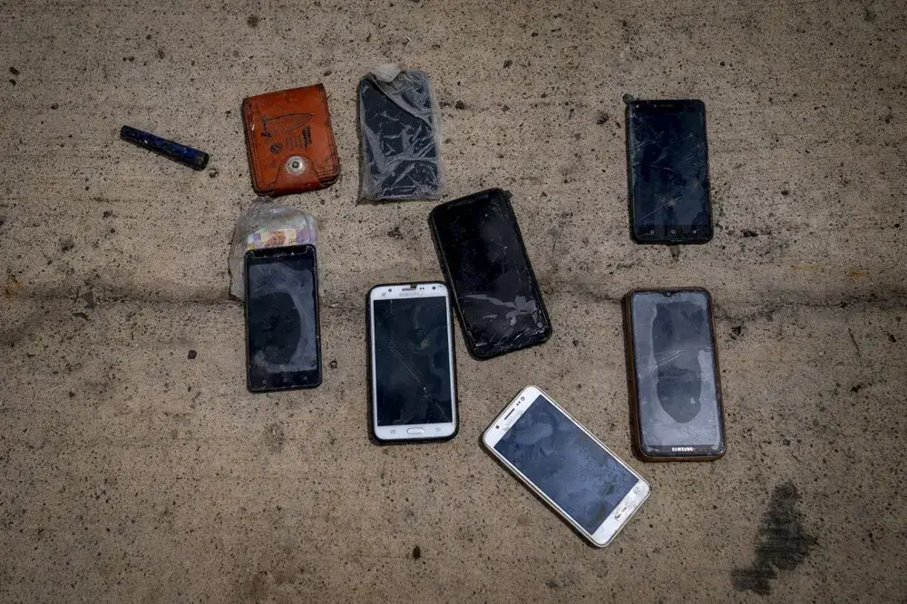 Phones and other items are placed on the ground by police officers as they inspect a boat where 15 Malians were found dead adrift in the Atlantic on Thursday, Aug. 20, 2020, in Gran Canaria island, Spain.&nbsp;Image by Emilio Morenatti/AP Photo. Spain, 2020.