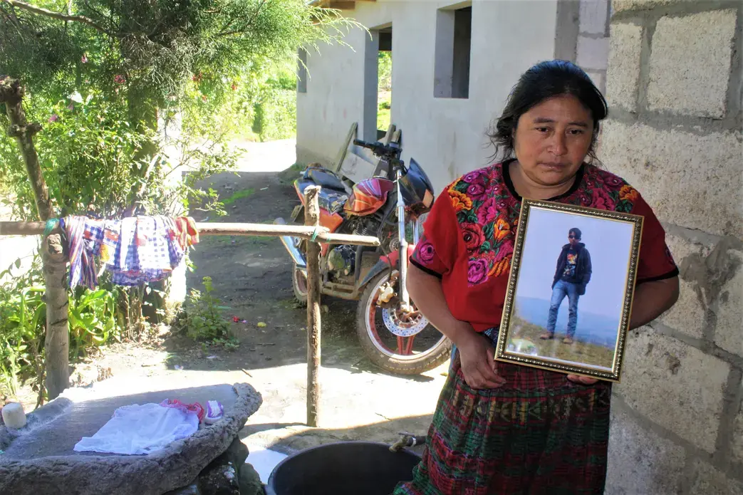 Lidia Carreto, 40, holds a framed photo of her 16-year-old son Davin, who died trying to immigrate illegally into the United States in June 2018 near Laredo, Texas. His body was repatriated to his home in the valley of Agua Blanca in San Juan, Ostuncalco. Image by Kristian Hernandez. Guatemala, 2018.