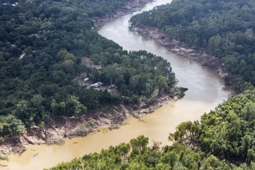 Storm water flowing south from Houston overflowed the banks of the Brazos River, sweeping away trees and earth, and flooding low-lying neighborhoods. Image by Alex MacLean. United States, 2017.