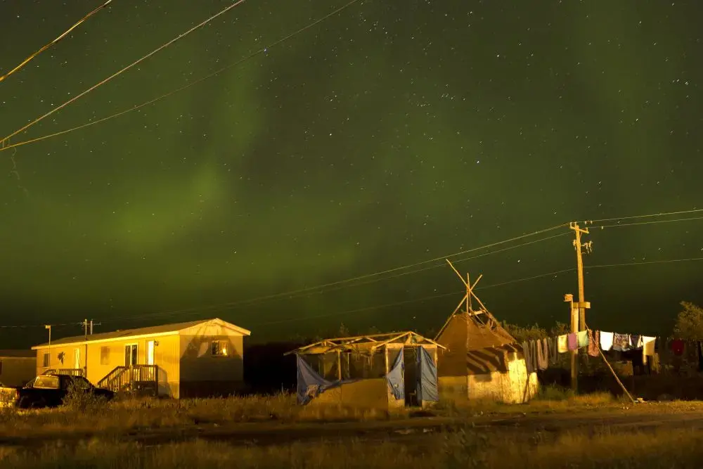 The northern lights fill the sky over the remote First Nations community of Attawapiskat. Attawapiskat is an isolated First Nation community located in northern Ontario, Canada, at the mouth of the Attawapiskat River on James Bay. On April 9, 2016, the community of approximately 2000 people declared a state of emergency after being overwhelmed with attempted suicides, over 100 attempts in a ten month period. Image by David Maurice Smith/Oculi. Canada, 2016.