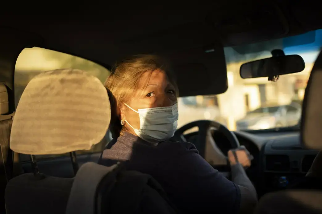 Norma Flores checks for traffic behind her as she drives to a grocery store near her home in Henderson, Nev., Tuesday, Nov. 10, 2020. Flores is a Mexican immigrant who spent two decades working as a waitress before COVID-19 descended and she lost her job. At night, she often lies awake, worrying about paying the rent, buying gas, getting enough food for her family. Image by Wong Maye-E / AP Photo. United States, 2020.