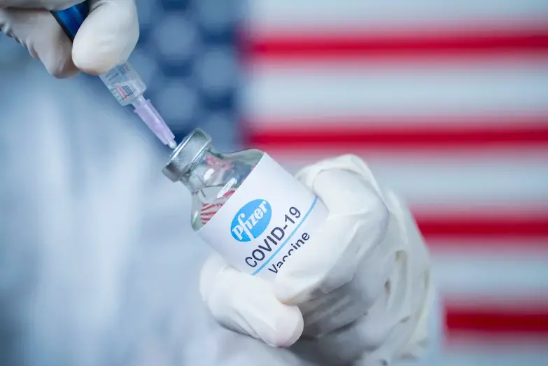 Doctor holding a Pfizer/Biontech vaccine. Image by lakshmiprasada S / Shutterstock. 2020.