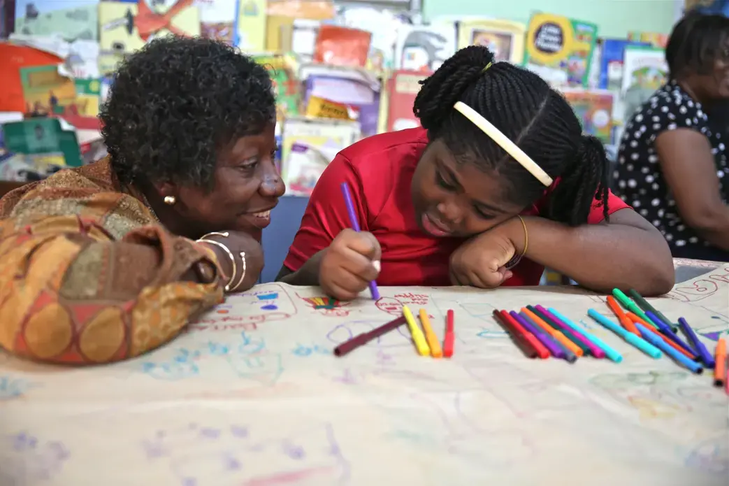 Dr. Claudette Crawford-Brown interacts with Shaniqua Long during an art therapy session at Shortwood Practising Infant, Primary and Junior High School in Kingston, Jamaica. Long's mother migrated to the United States. Image by Sabriya Simon. Jamaica.