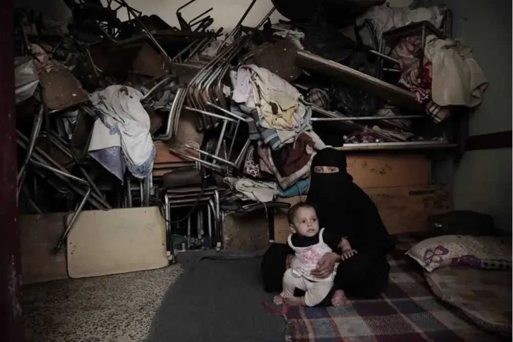 A woman sits with her baby inside a shelter for displaced persons in Ibb. Image by Nariman El-Mofty/AP Photo. Yemen, 2018.