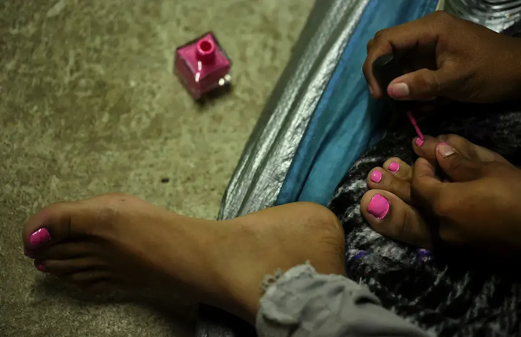 Gabriela, 22, left, and friend Daniela, 19, talk in a shelter in Tijuana. Gabriela, mother of two children, was shot several times in El Salvador. They talked about the risks women can face in their home country, including sexual assault, violence and death. The women fled and were in the process of applying for asylum. Image by Erika Schultz. Mexico, 2019.
