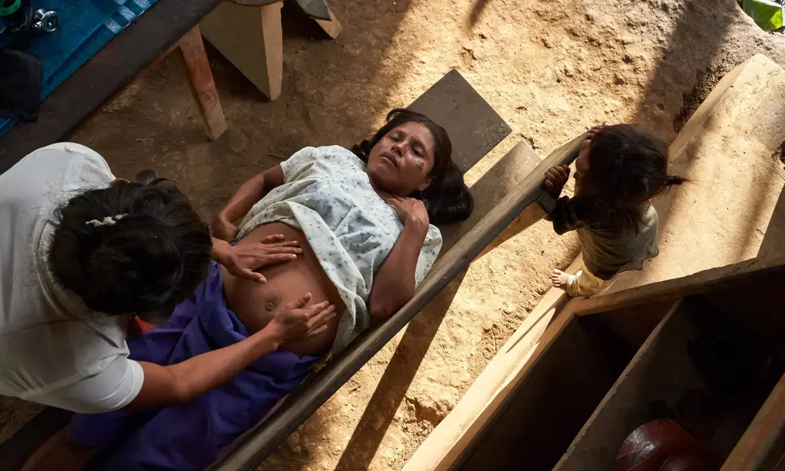 Vero controls the fetal position of a woman who is seven months pregnant. Image by Pablo Albarenga. Ecuador, undated.