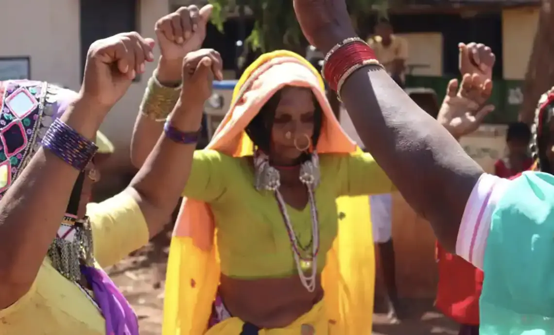 Women dance with their arms raised.