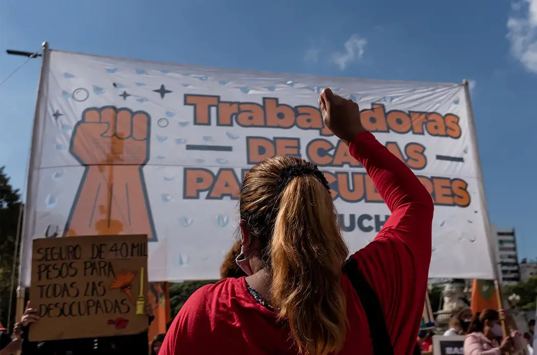 Someone, with their back to the camera, raises their fist during a protest.